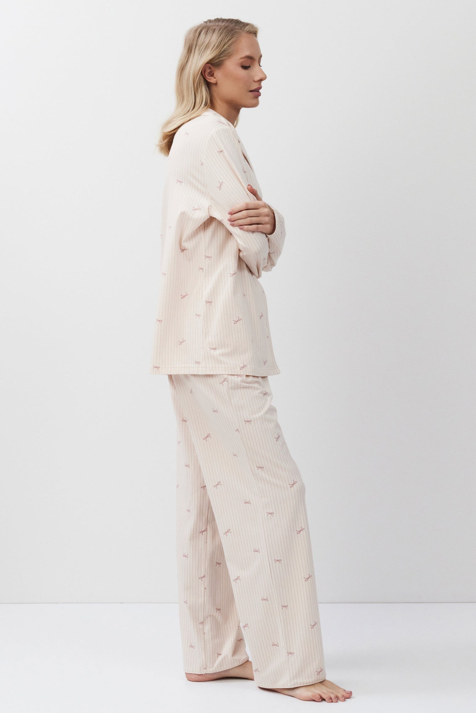 Woman wearing a pink-colored pajama set against a white background