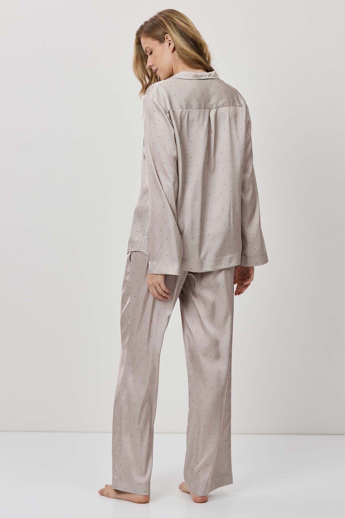Person wearing a beige pajama set against a white background