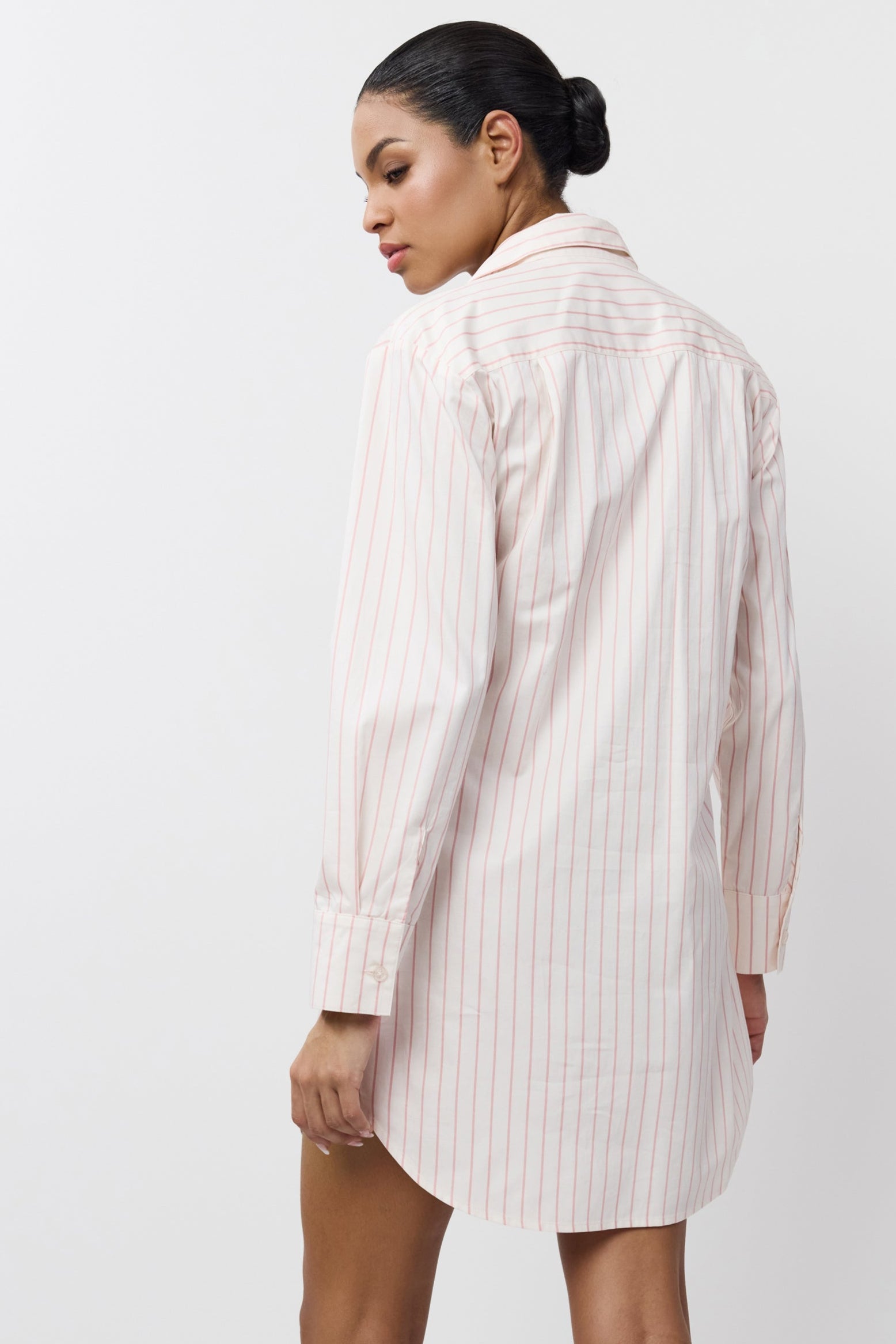 Woman wearing a pink-colored striped shirt against a white background