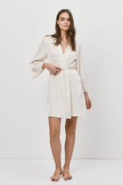 Woman wearing a white gown with bell sleeves against a white background