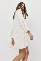 Woman wearing a white gown with long sleeves on a plain background