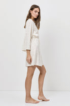 Woman wearing a white gown with long sleeves on a white background