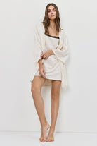 Woman wearing a white nightdress and gown on a plain background