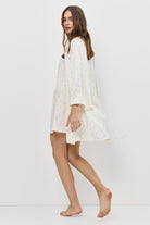 Woman wearing a white nightgown on a plain background