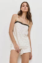 Woman wearing a white lace-trimmed pajama set against a plain background