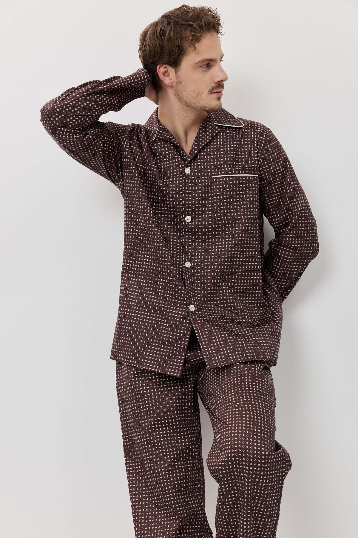 Man wearing a brown checkered pajama set against a white background