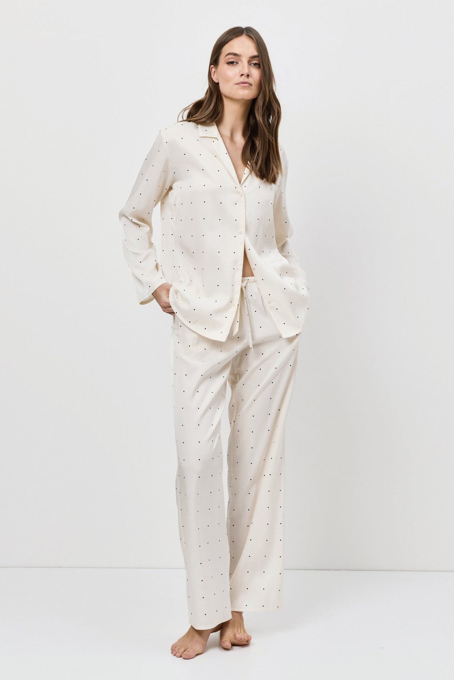 Woman wearing a white pajama set against a plain background