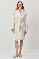 Woman wearing a cream-colored robe against a white background
