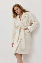 Woman wearing a cream-colored robe against a white background