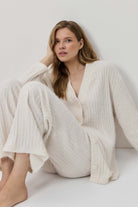 Woman wearing a white knit outfit sitting on a white background