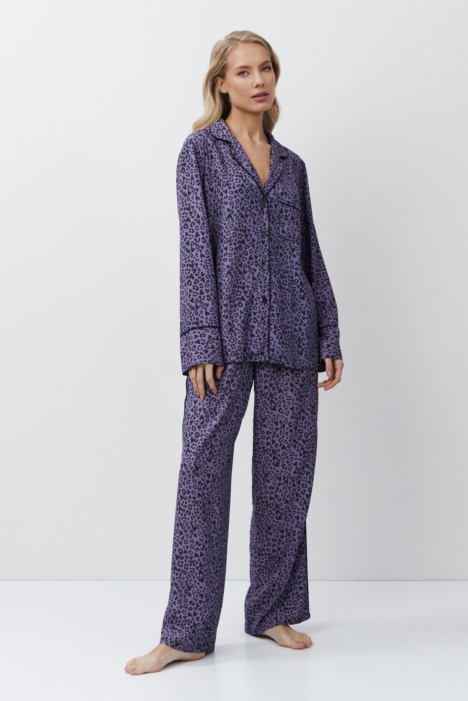 Woman wearing a purple patterned pajama set on a white background