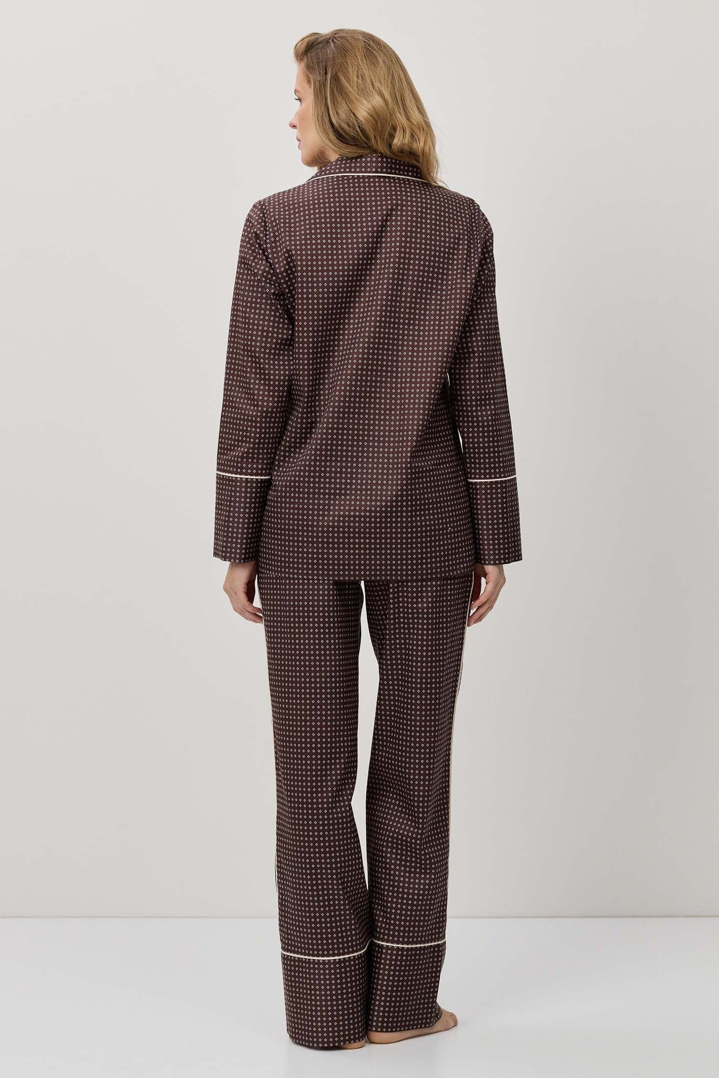 Person wearing a brown checkered pajama set on a white background