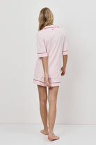 Woman wearing a pink pajama set against a white background