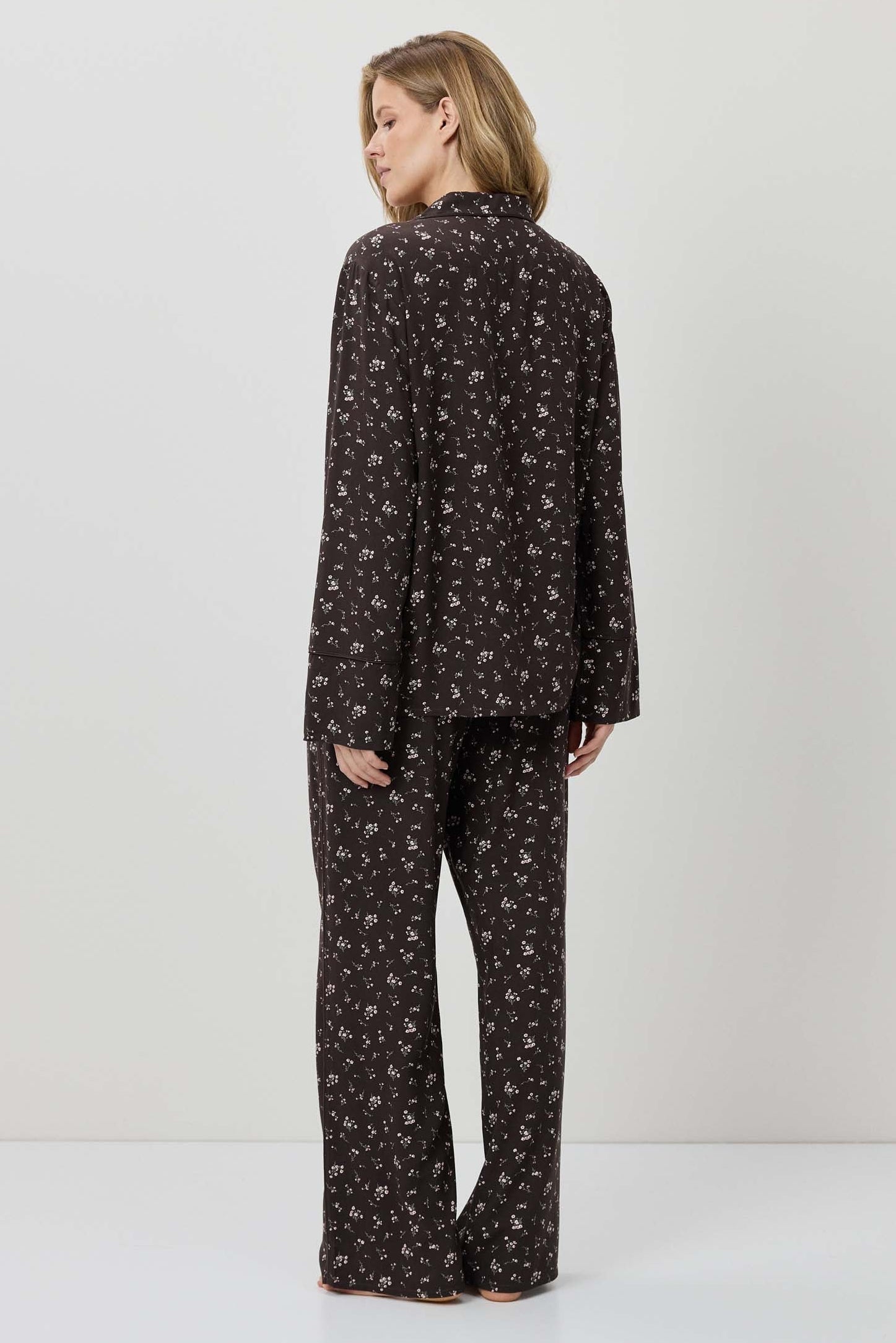 Woman wearing a black patterned pajama set on a white background