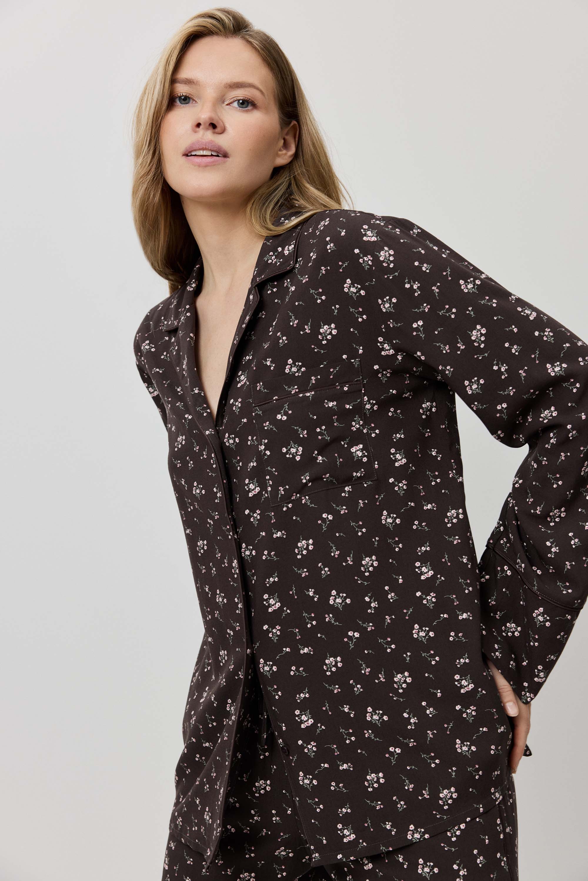 Woman wearing a dark floral patterned shirt dress against a plain background