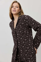 Woman wearing a dark floral patterned shirt dress against a plain background