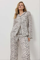 Woman wearing a leopard print pajama set against a plain background