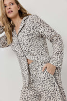 Woman wearing a leopard print outfit against a plain background