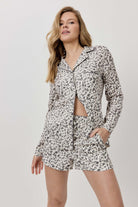 Woman wearing a leopard print pajama set on a plain background