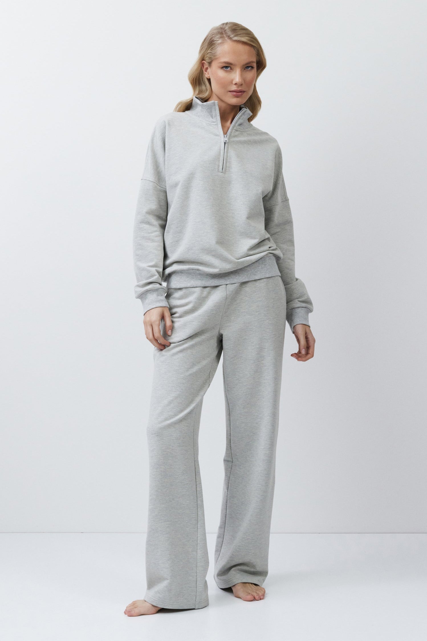 Woman wearing a gray tracksuit on a white background