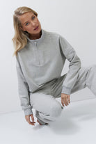 Woman wearing a gray sweatshirt and pants on a white background