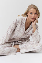 Woman wearing a plaid pajama set sitting on a white background