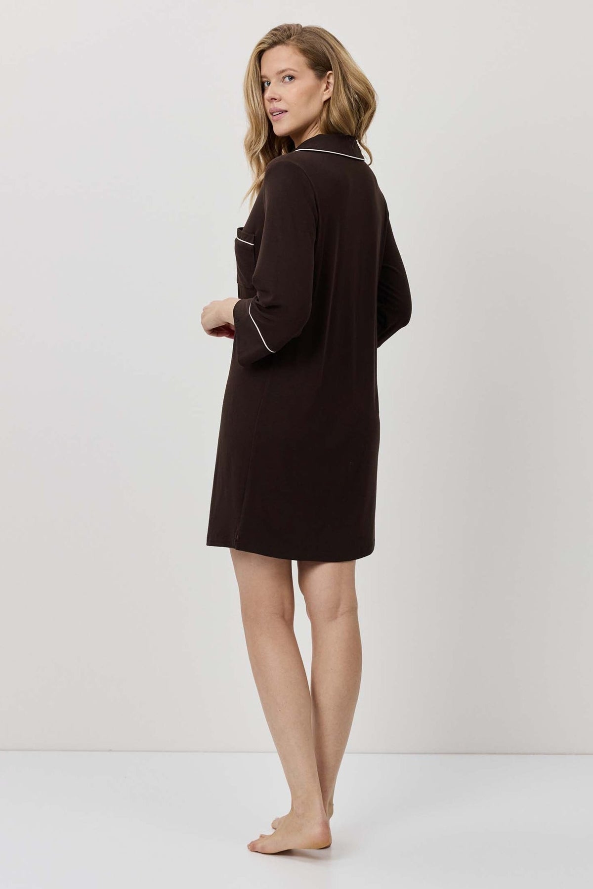 Woman wearing a dark brown dress against a white background