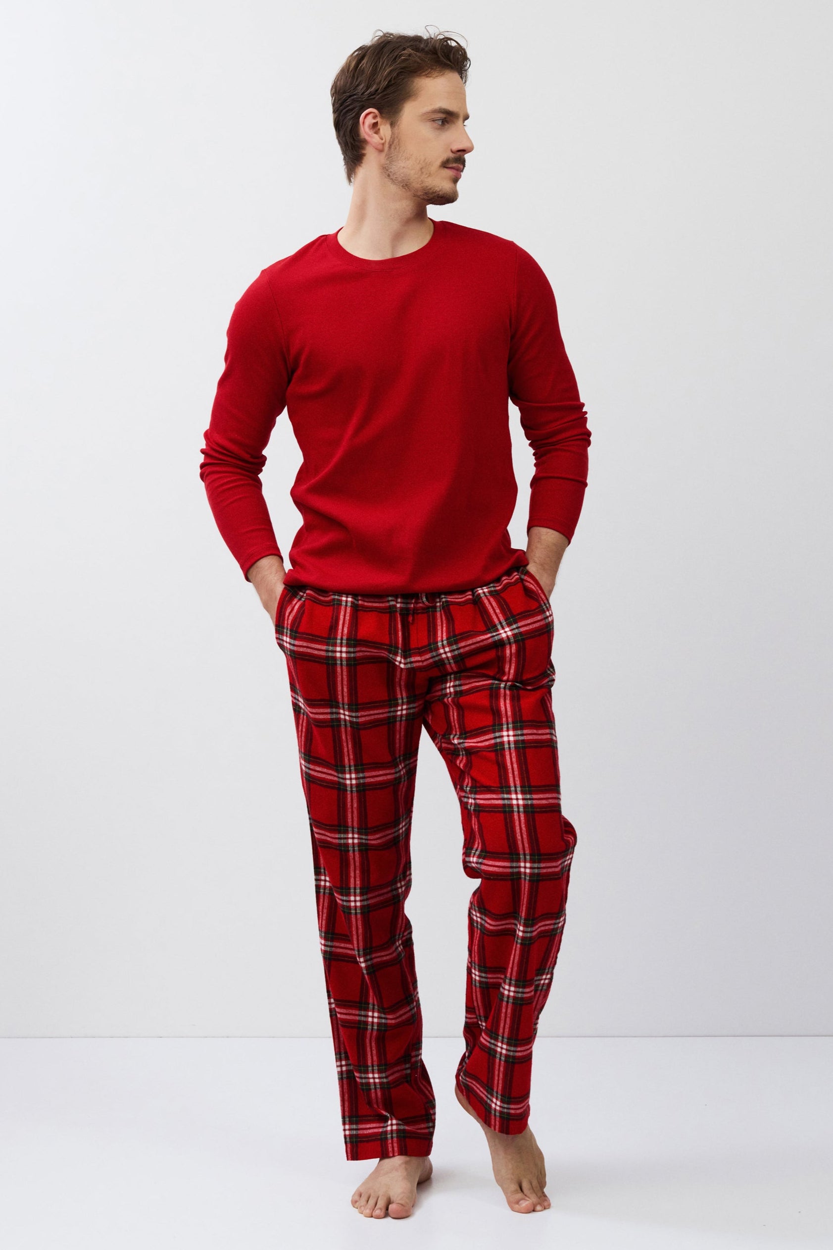 Man wearing a red long-sleeve shirt and plaid pants on a white background
