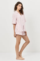 Woman wearing a pink floral pajama set on a white background