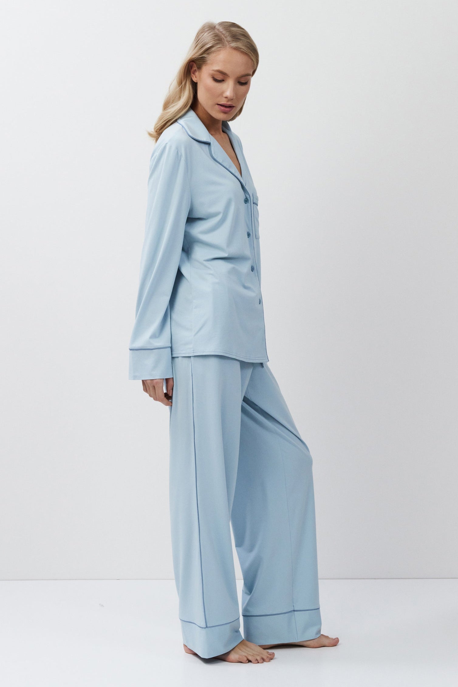 Woman wearing a light blue pajama set against a white background