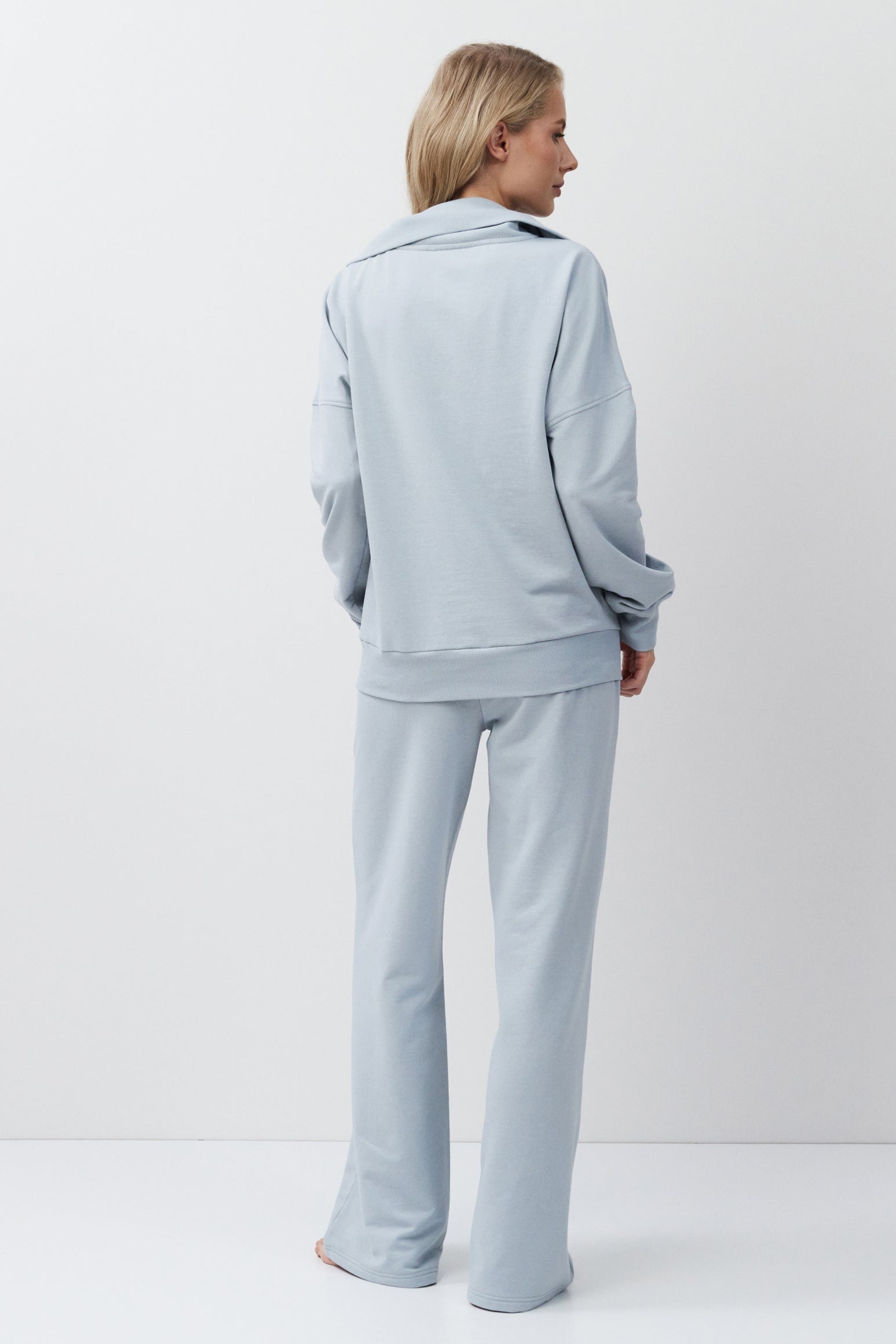 Woman wearing a light blue tracksuit against a white background
