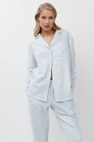 Woman wearing light blue striped pajamas against a white background