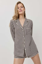 Woman wearing a black and white striped pajama set on a plain background
