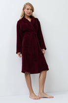 Woman wearing a burgundy robe against a white background