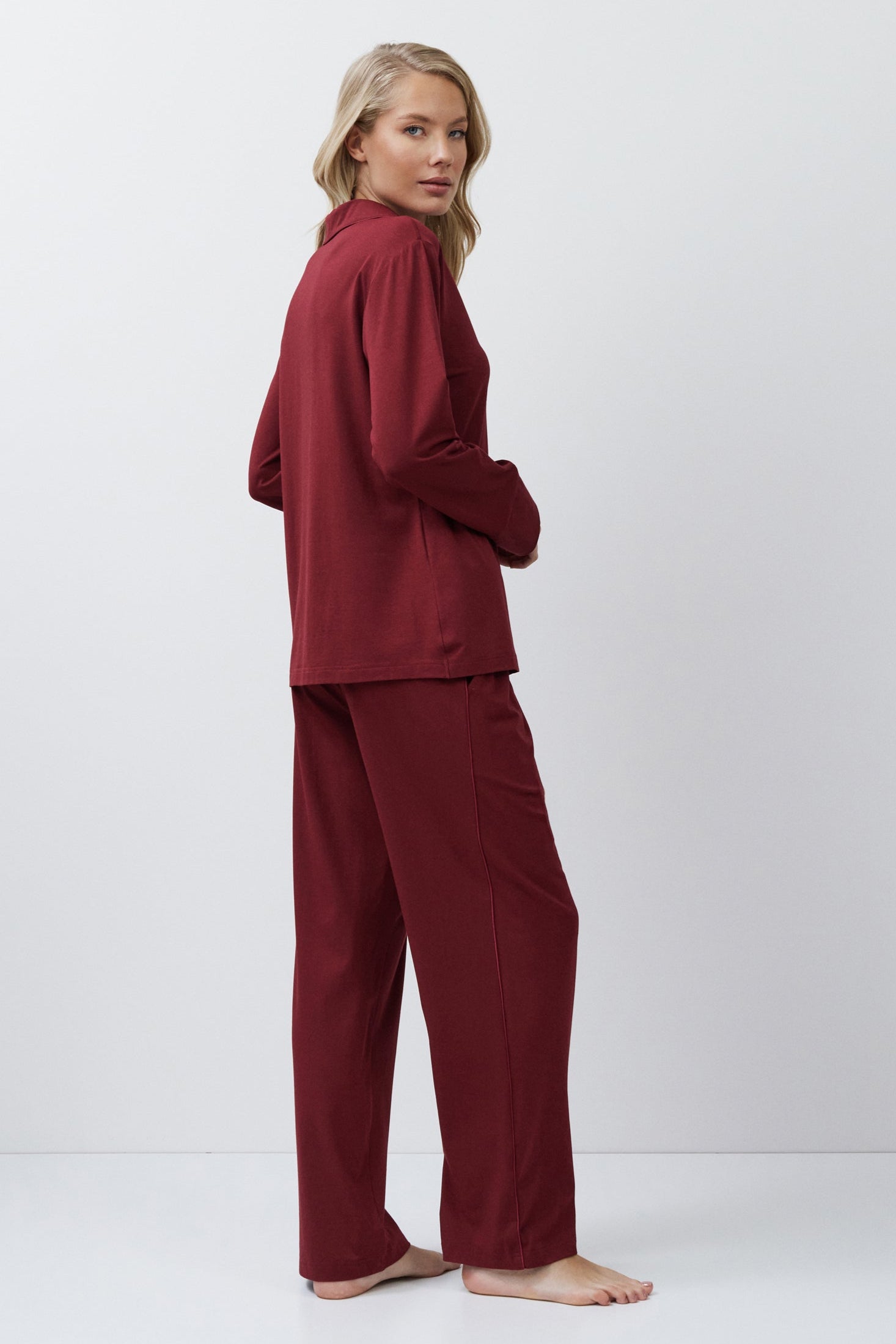 Person wearing a burgundy pajama set on a white background