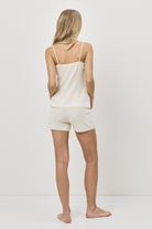 Woman wearing a beige tank top and shorts set on a white background