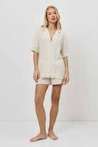 Woman wearing a butter yellow pajama set on a plain background