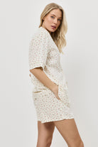 Woman wearing a butter yellow floral pajama set on a plain background