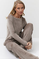 Woman wearing a capucine ribbed lounge set sitting on a white surface.