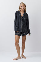 Woman wearing a gray striped pajama set on a white background