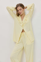 Woman wearing a light yellow pajama set against a white background
