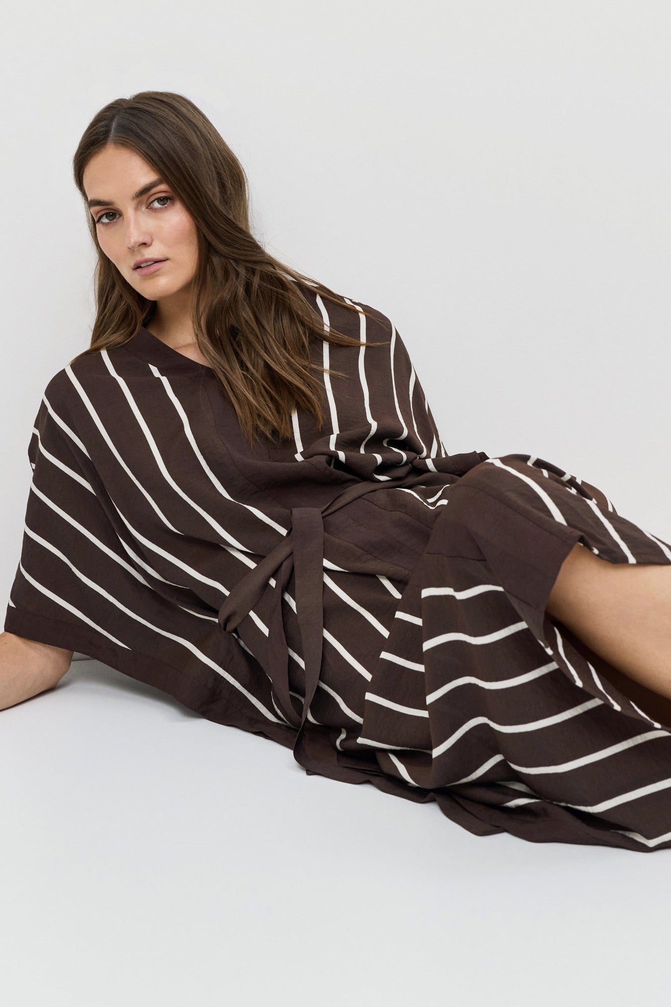 Woman wearing a brown and white striped dress on a white background
