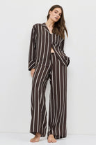 Woman wearing a brown and white striped resort wear set on a white background