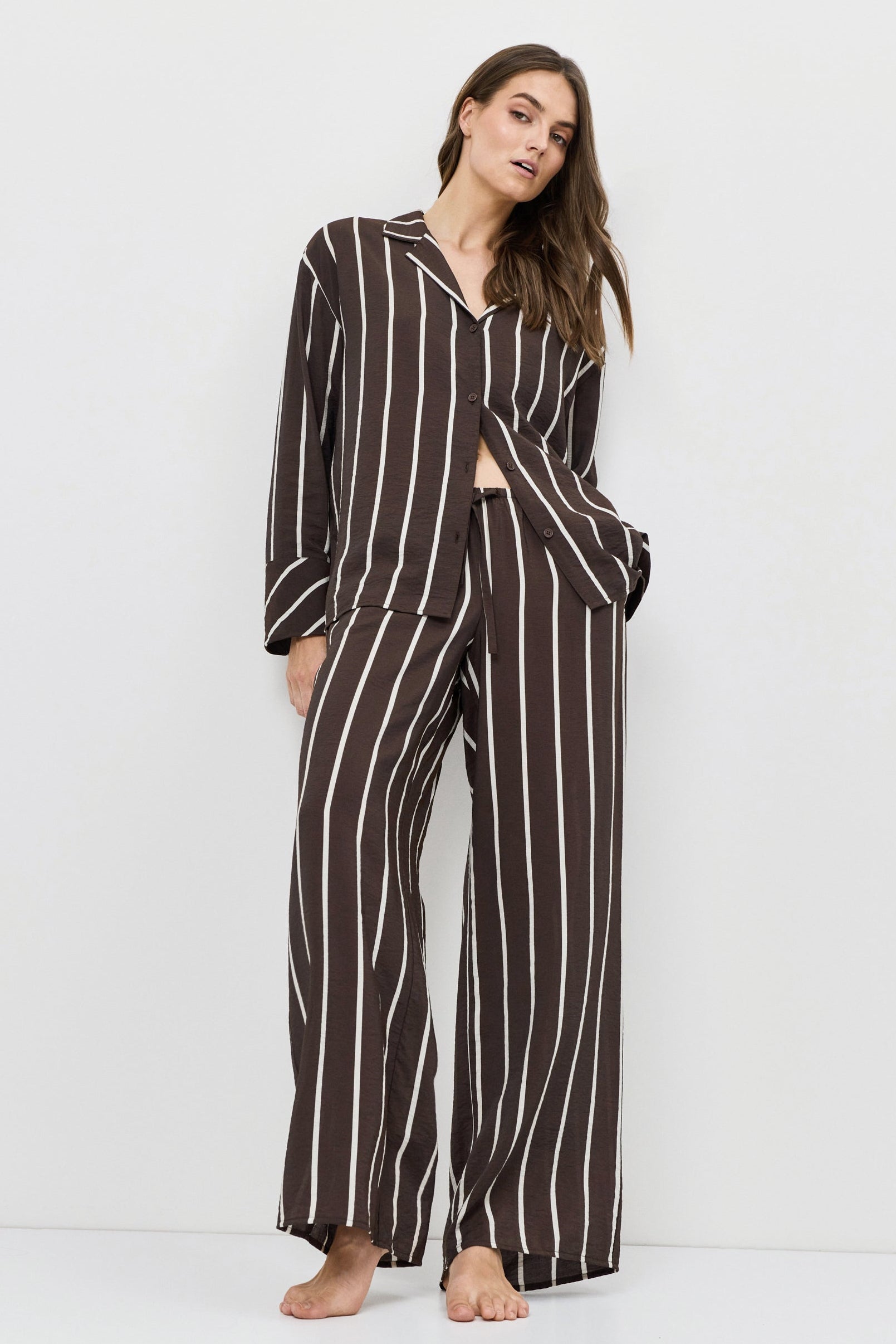 Woman wearing a brown and white striped resort wear set on a white background