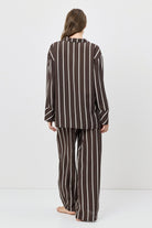Person wearing a brown and white striped pajama set on a white background