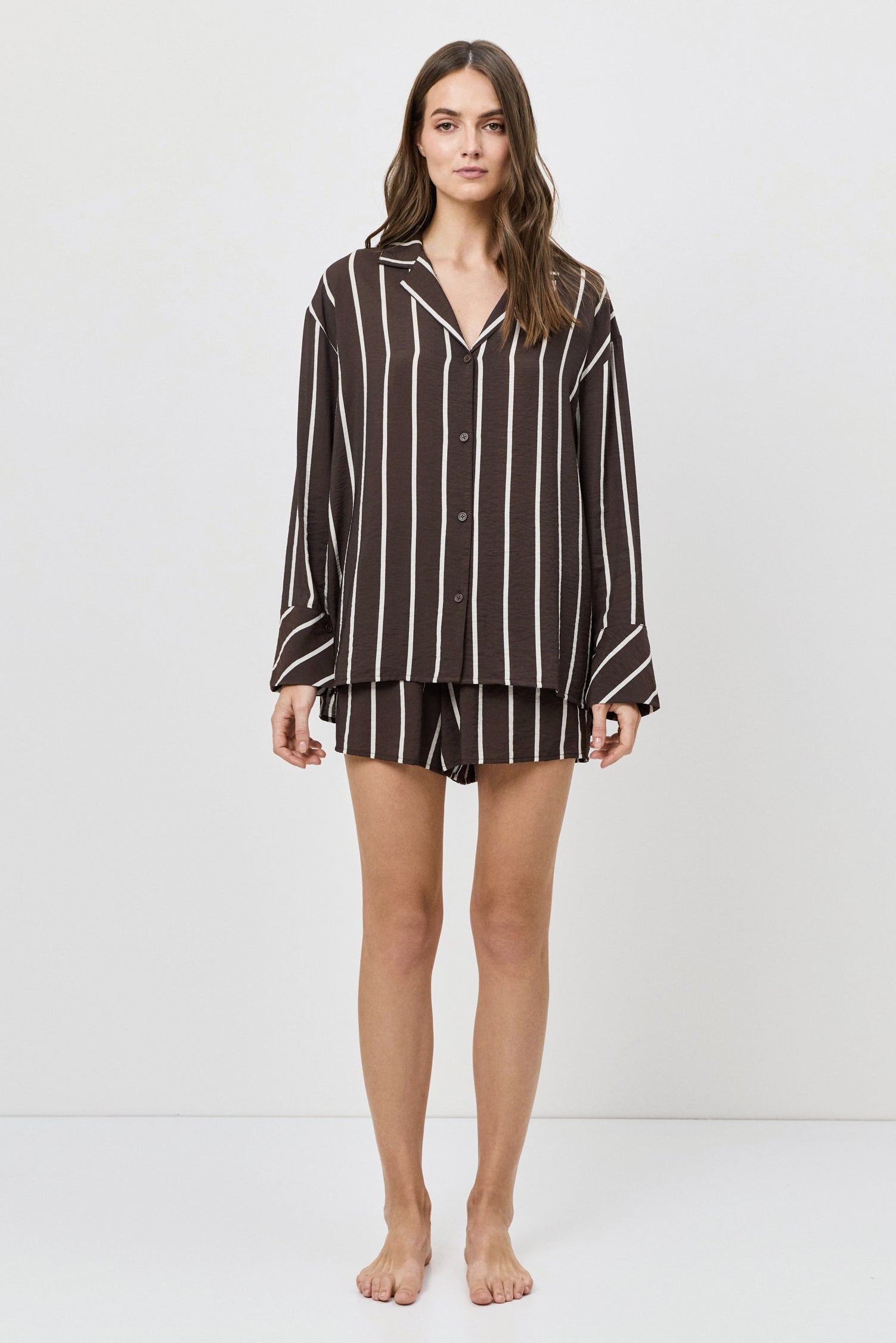 Woman wearing a brown and white striped shirt and shorts on a white background