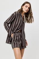 Woman wearing a brown and white striped outfit on a plain background