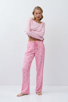 Woman wearing pink pajama set with heart patterns on a white background