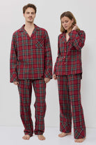 Two people wearing red plaid pajamas standing against a white background