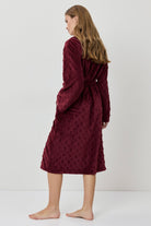 Woman wearing a burgundy textured dress against a white background